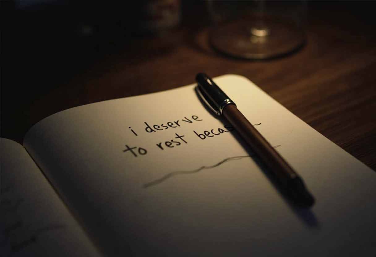 Dimly lit journal open with a pen resting on the page, showing the handwritten bedtime affirmation